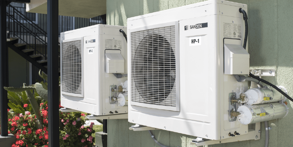 Exterior heat pump units installed at a multifamily residential building, providing high-efficiency electric heating and cooling as part of a building electrification project.