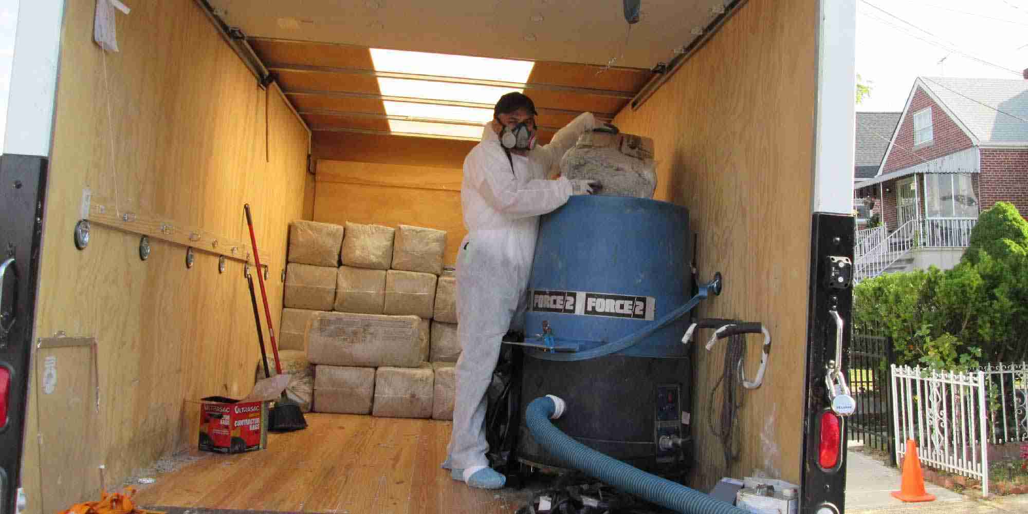 Weatherization crew installing cellulose insulation using a blower machine in a residential home