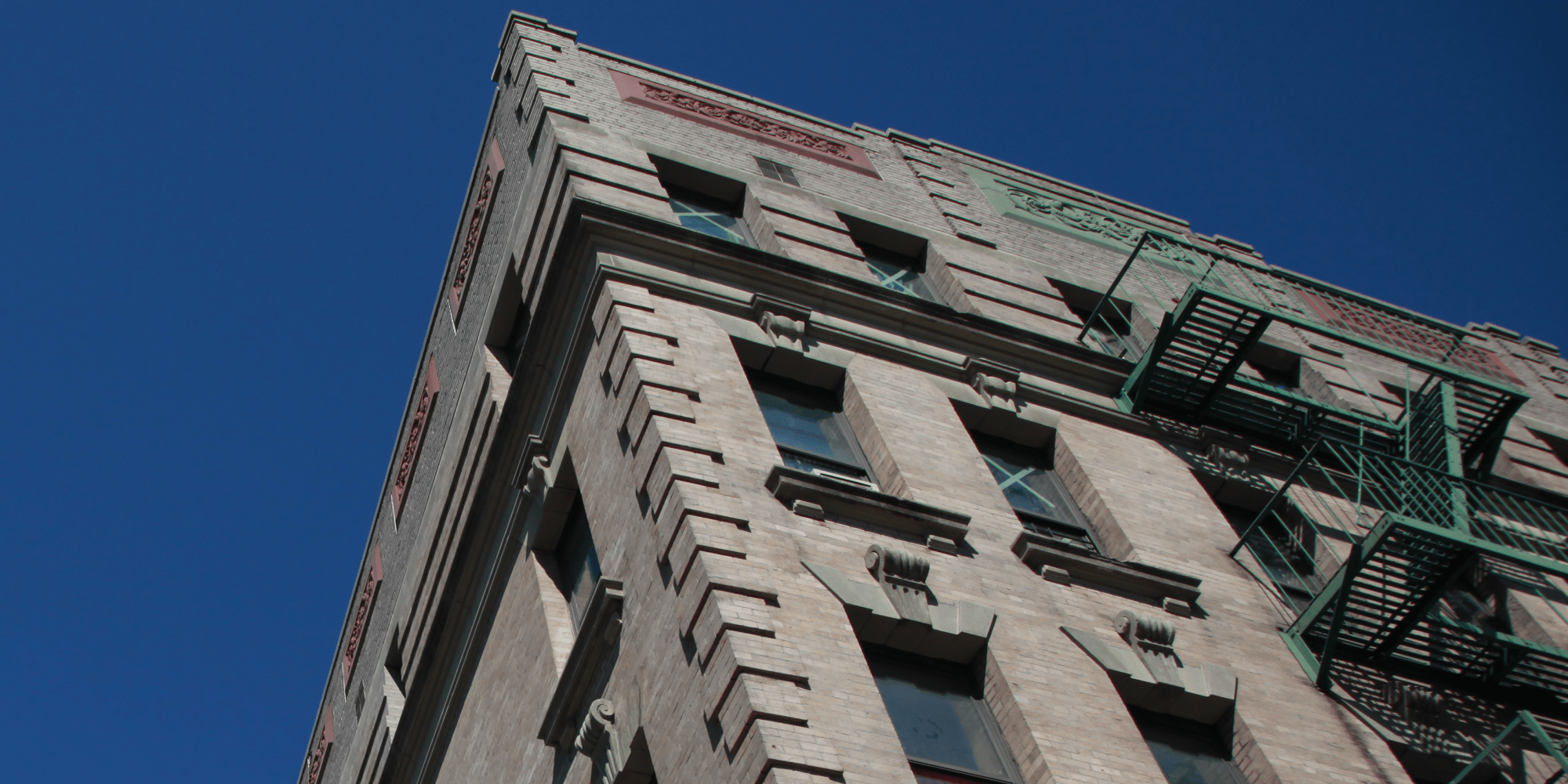 Exterior view of a multifamily building in New York City with brick facade and fire escape