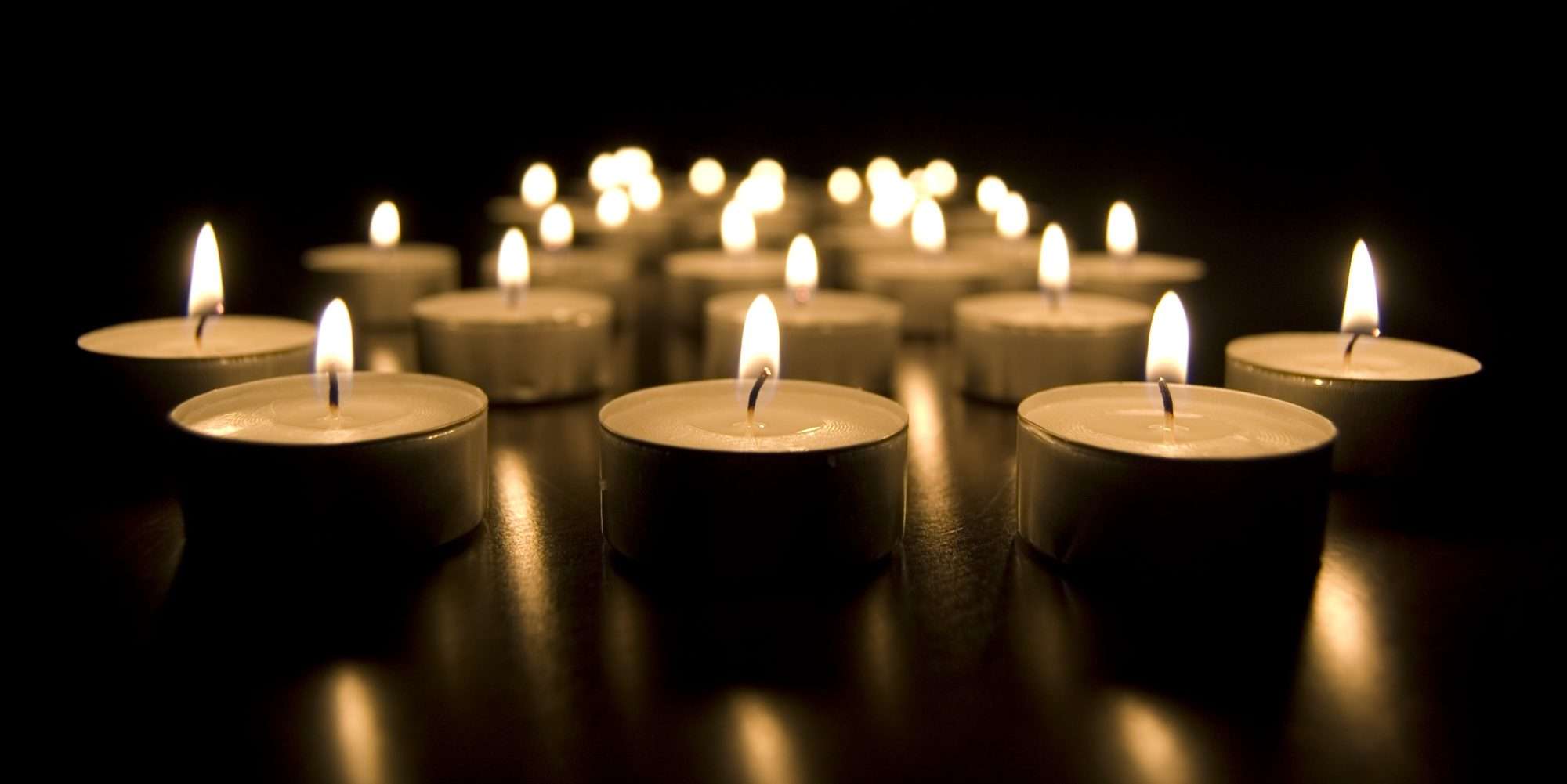 Lit candles arranged in a dark setting symbolizing remembrance