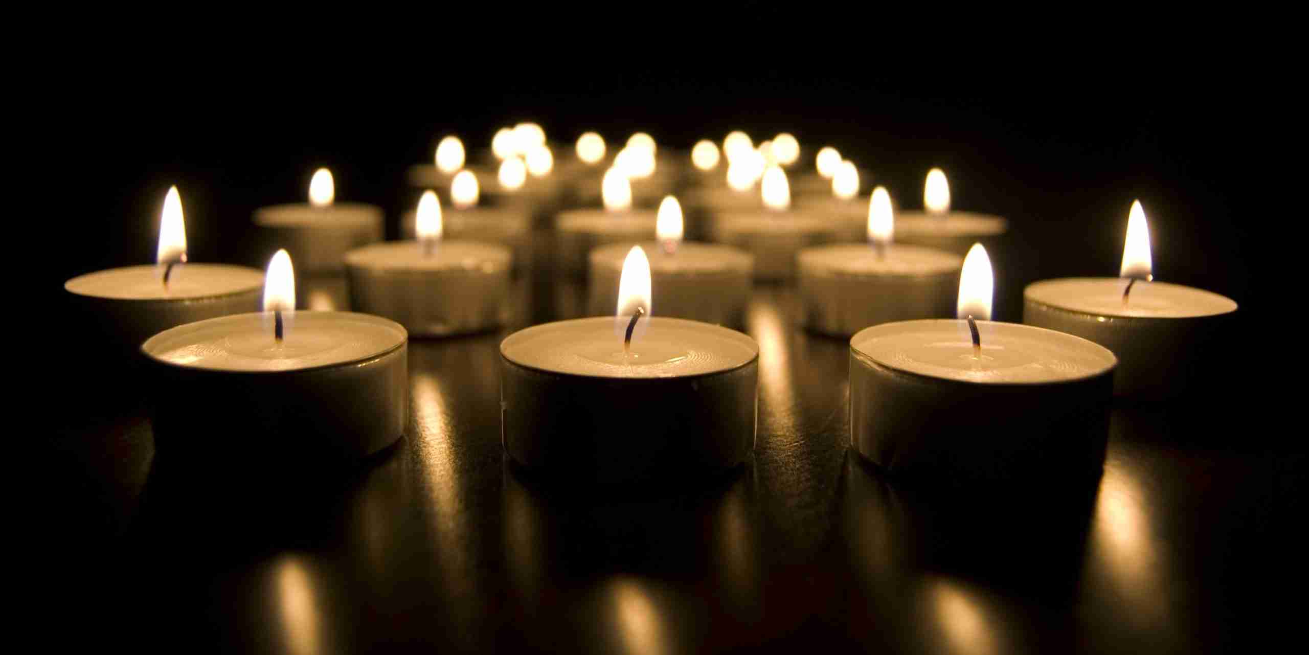 Lit candles arranged in a dark setting symbolizing remembrance
