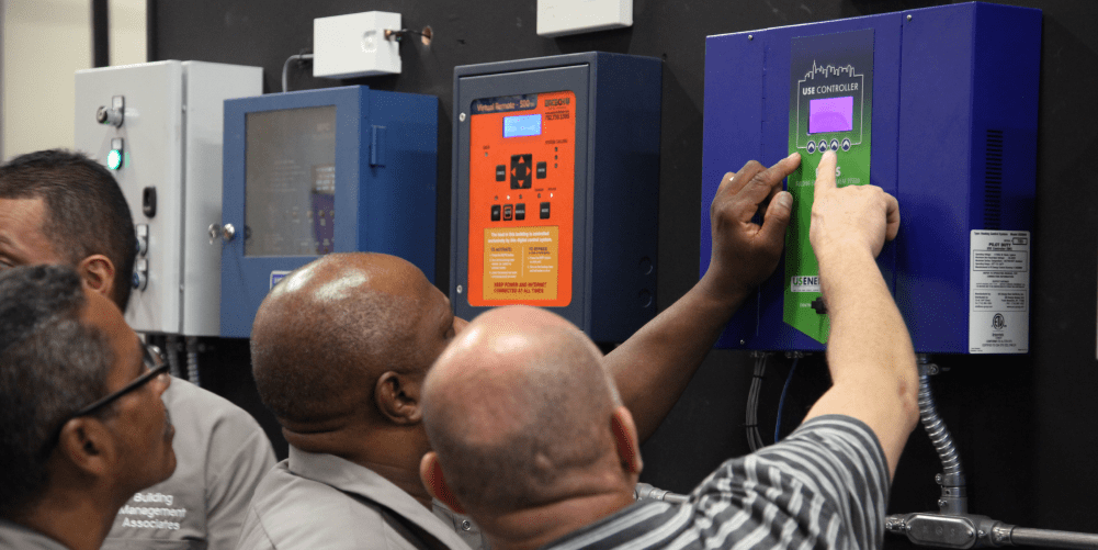 Students examining an energy management system control panel in a Bronx training lab