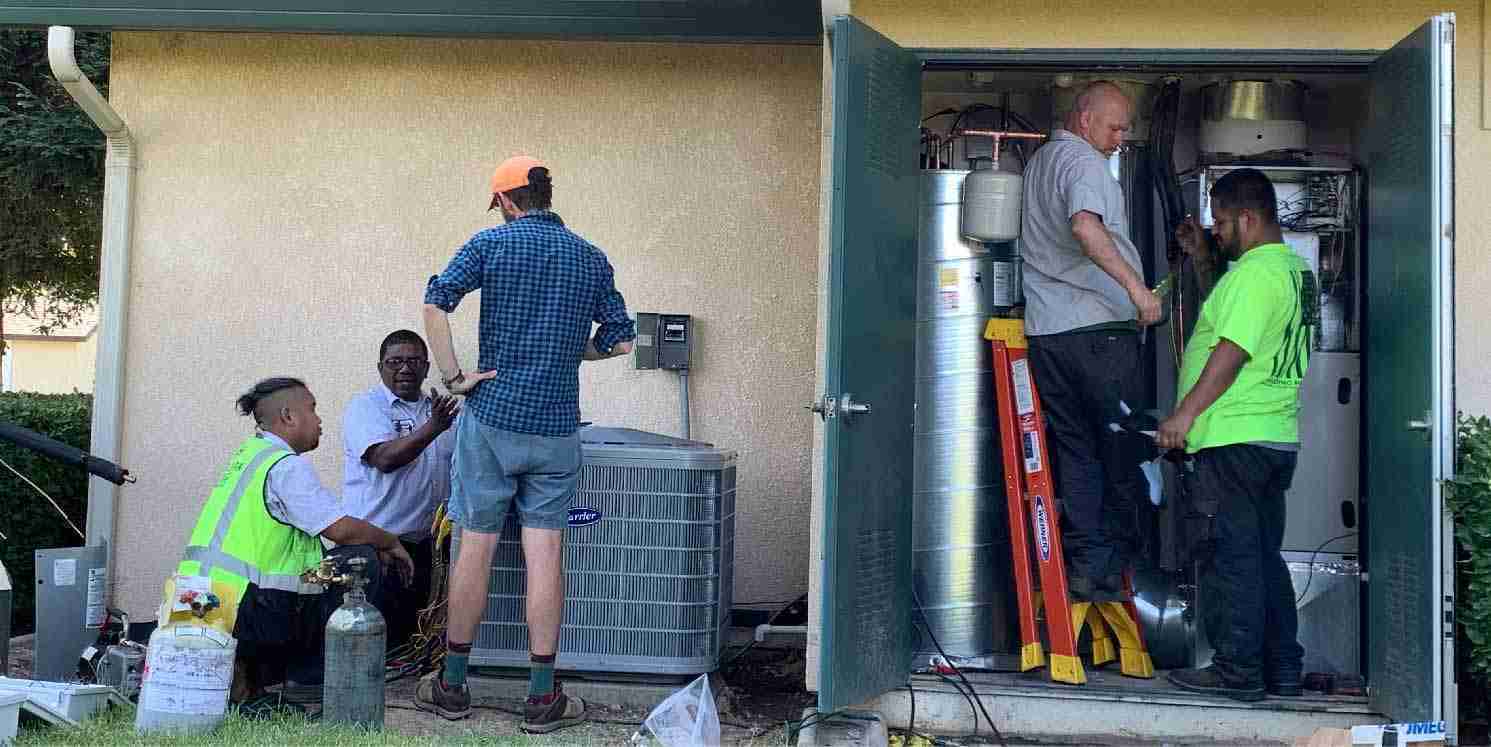 Technicians installing low-GWP mechanical HVAC and water heating module