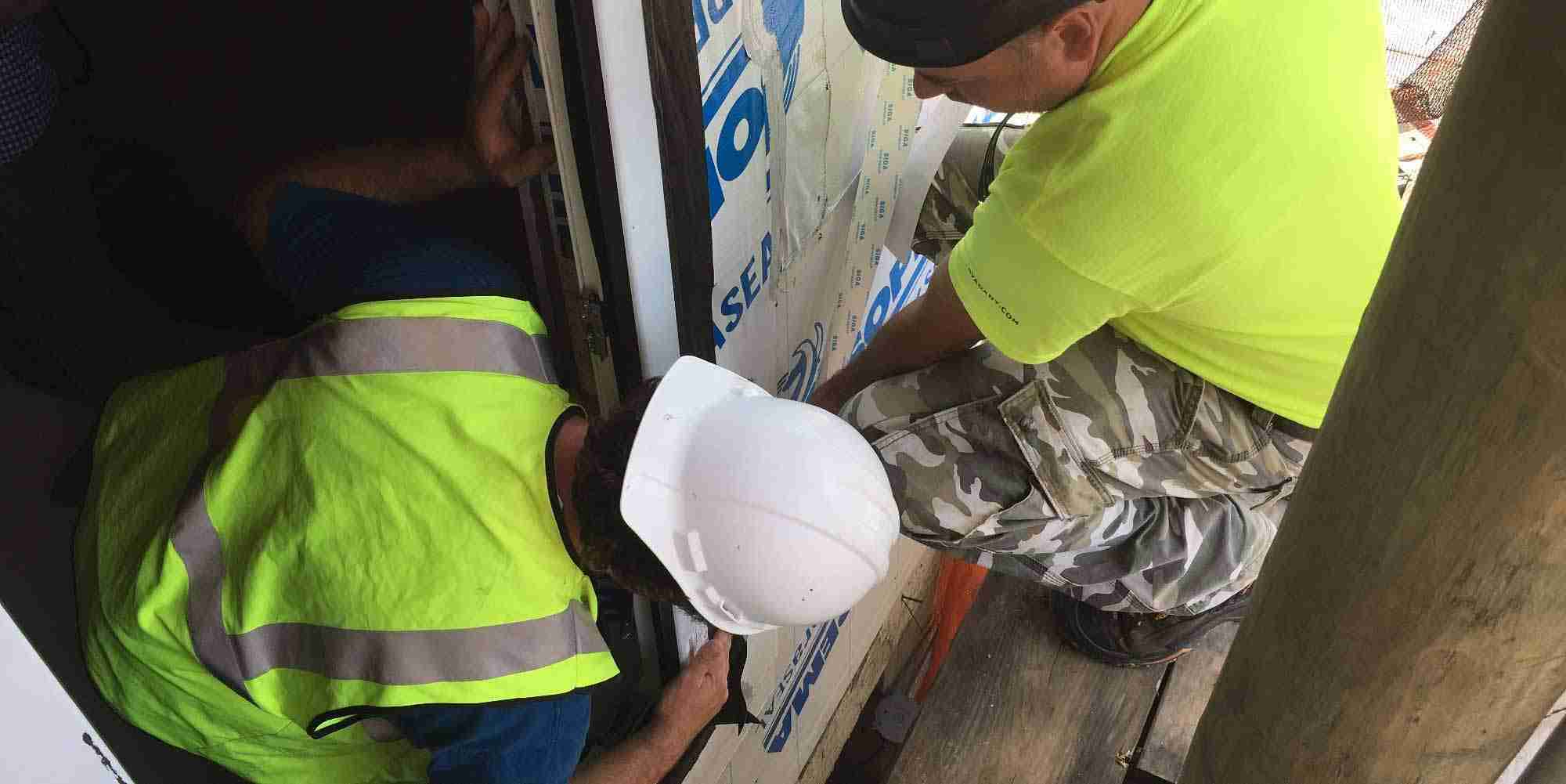 Construction workers sealing the exterior building envelope of a multifamily Passive House project during installation in New York