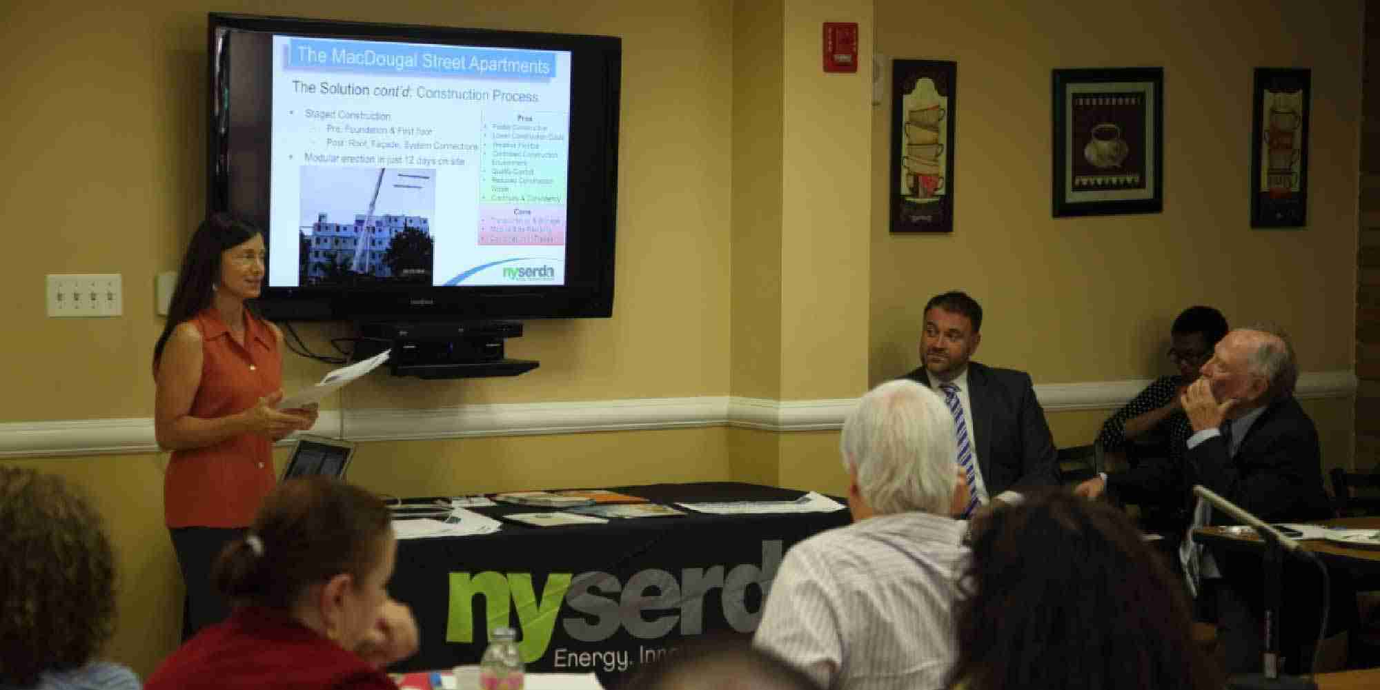 Presenter speaking to an audience during a NYSERDA Building Celebration at MacDougal Street Apartments in Brooklyn