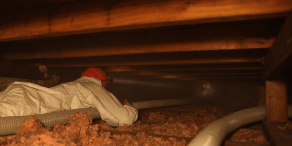 Weatherization installer blowing loose-fill cellulose insulation into a cockloft attic in the Bronx, New York