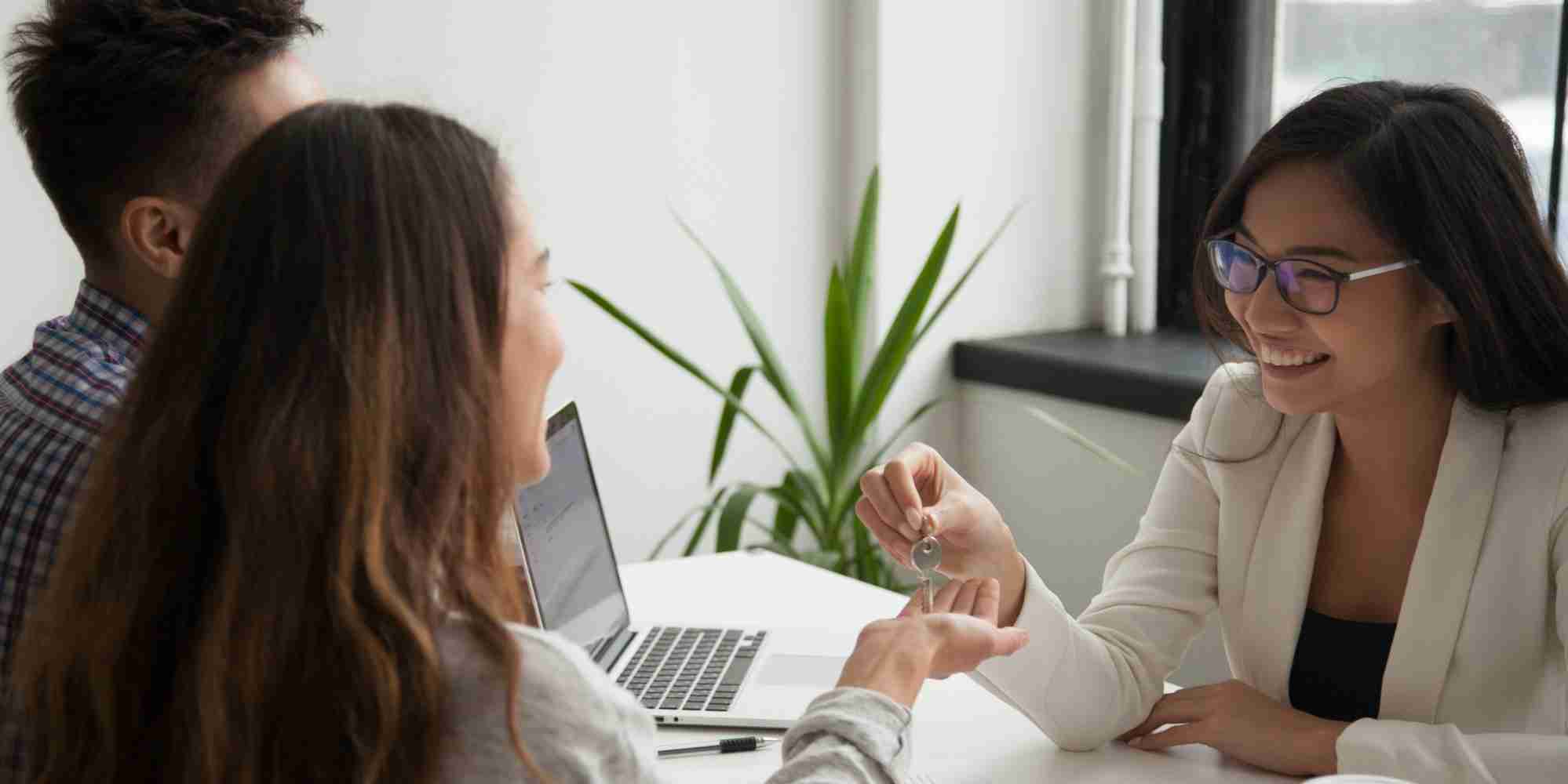 Real estate agent handing house keys to a client during a home purchase meeting