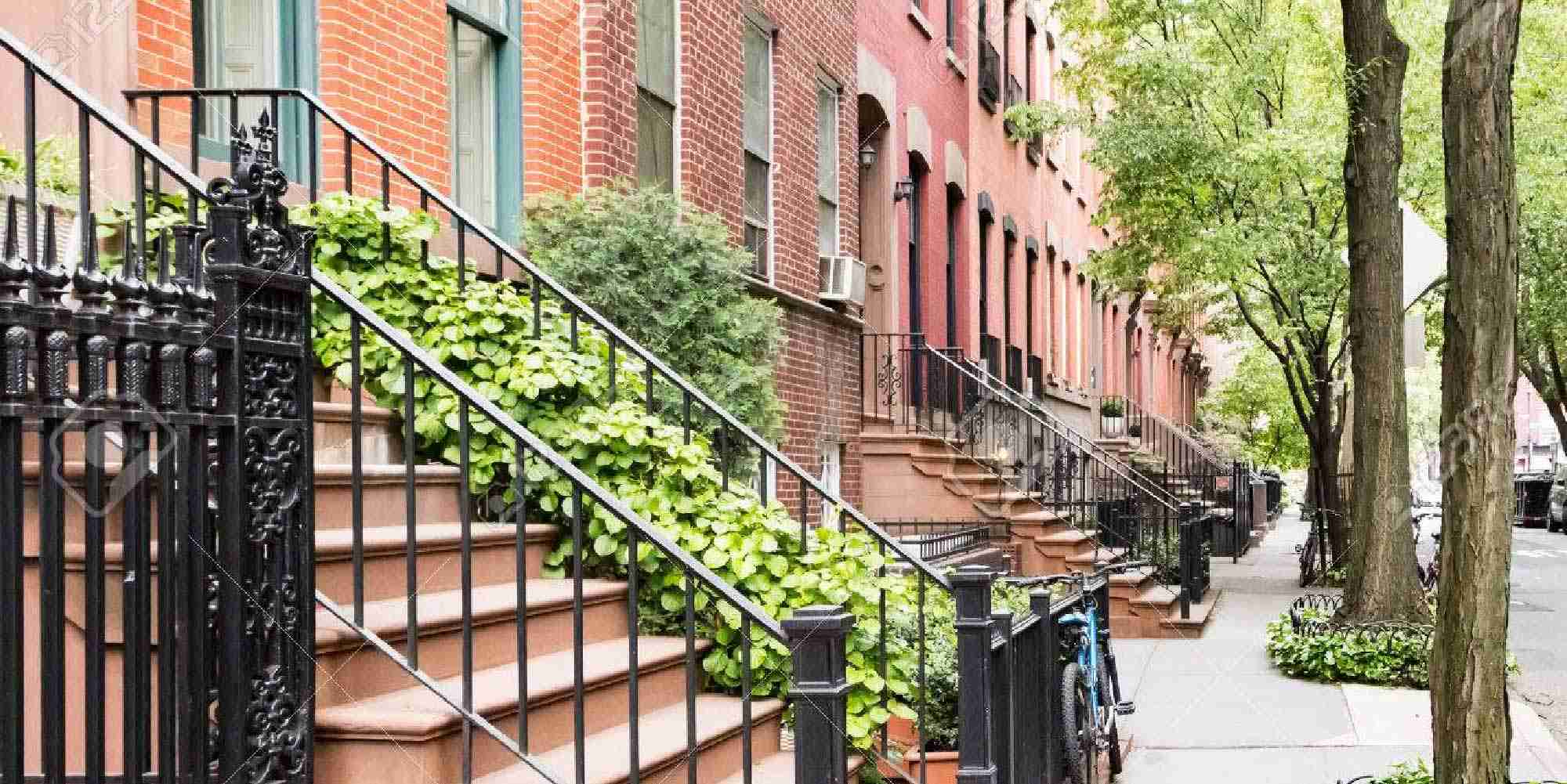 Row of classic Brooklyn brownstone homes with stoops and tree-lined sidewalk