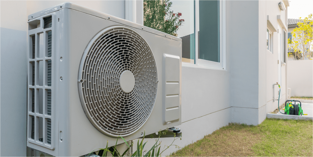 Exterior heat pump unit installed next to a residential building