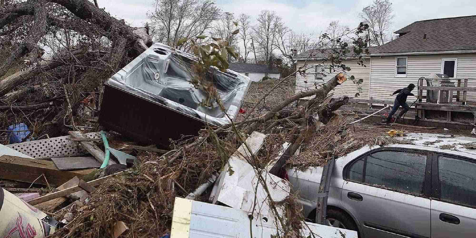 Storm debris including a fallen tree, damaged car, and displaced hot tub outside a home after Hurricane Sandy