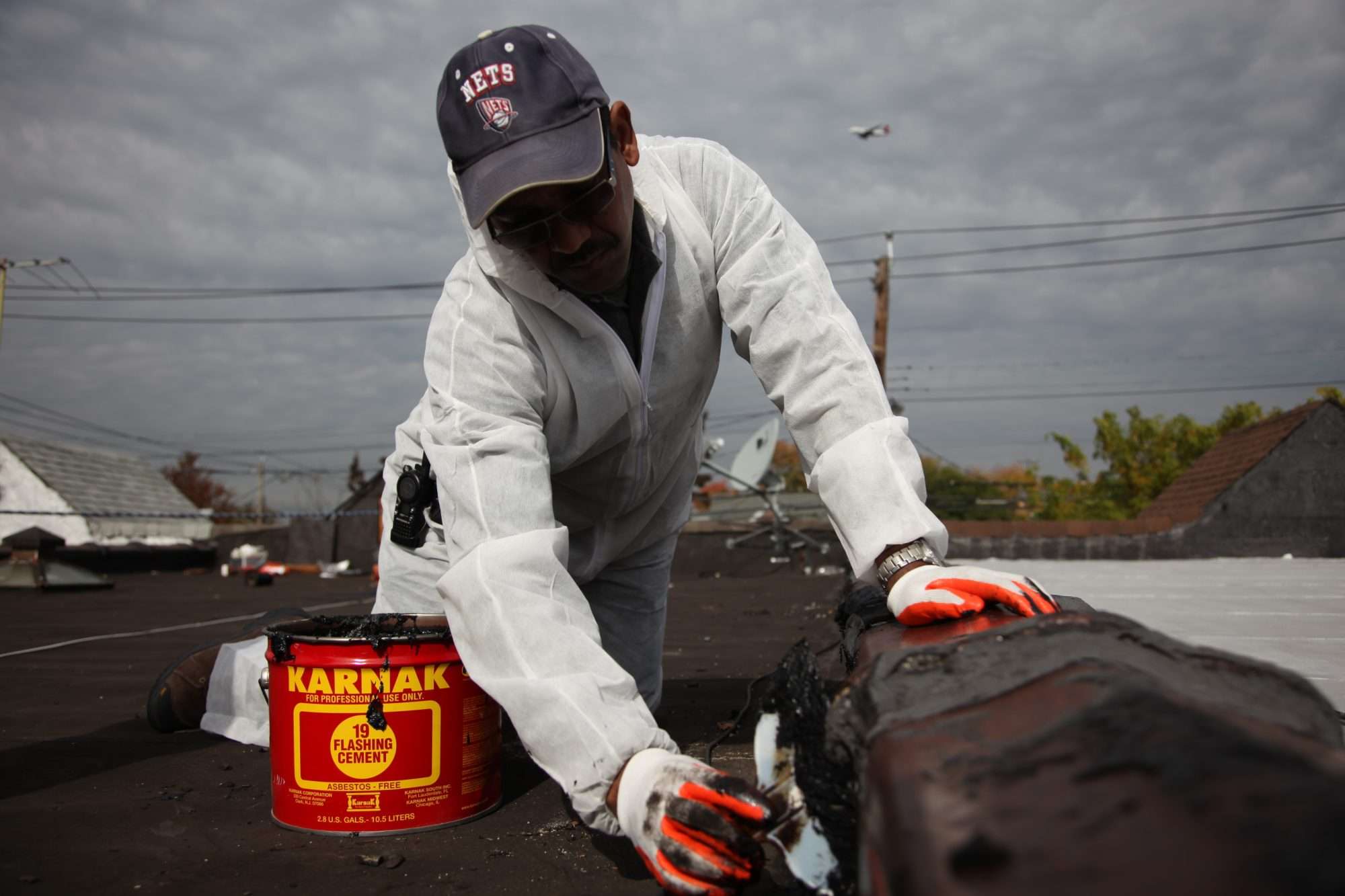 Weatherization Assistance Program worker sealing capping stones with flashing cement during building maintenance