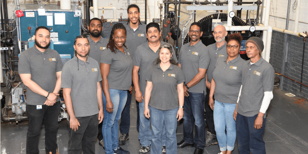Association for Energy Affordability Weatherization Assistance Program team standing in a boiler room with heating equipment